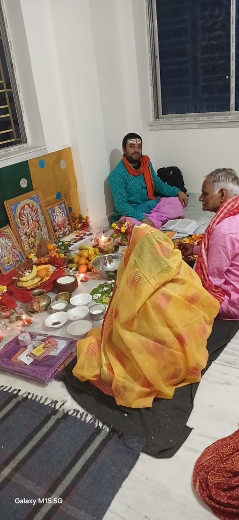 Hindu priest performing a family puja with devotees for Goddess Durga/Laxmi in Kolkata home.